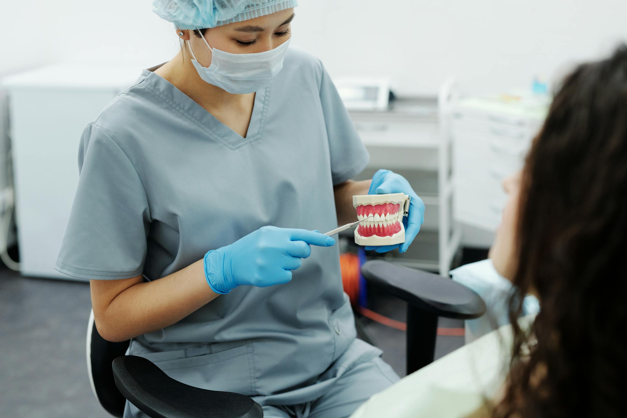 A dentist demonstrates proper oral care to a patient with dental model in a clinic.