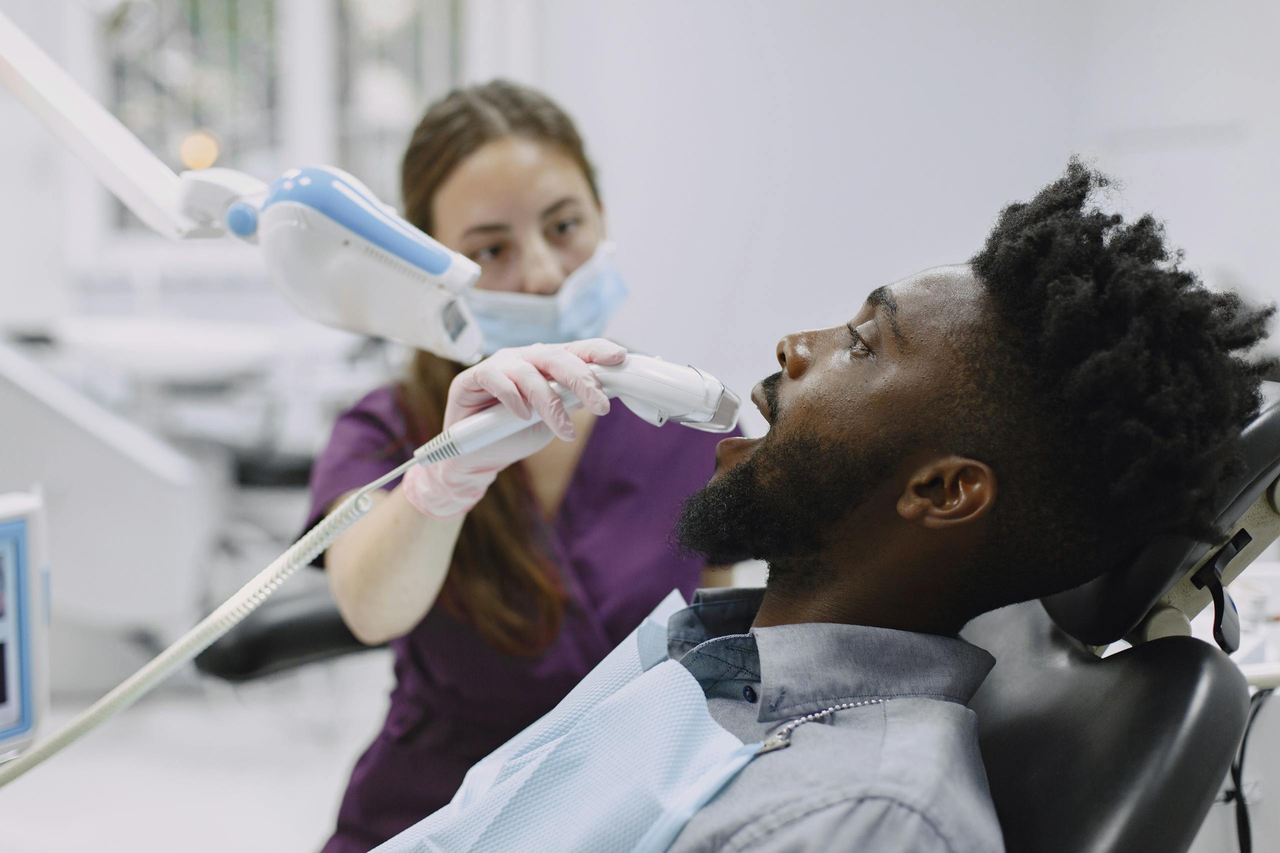 A dentist performing a checkup using advanced dental tools on a patient.