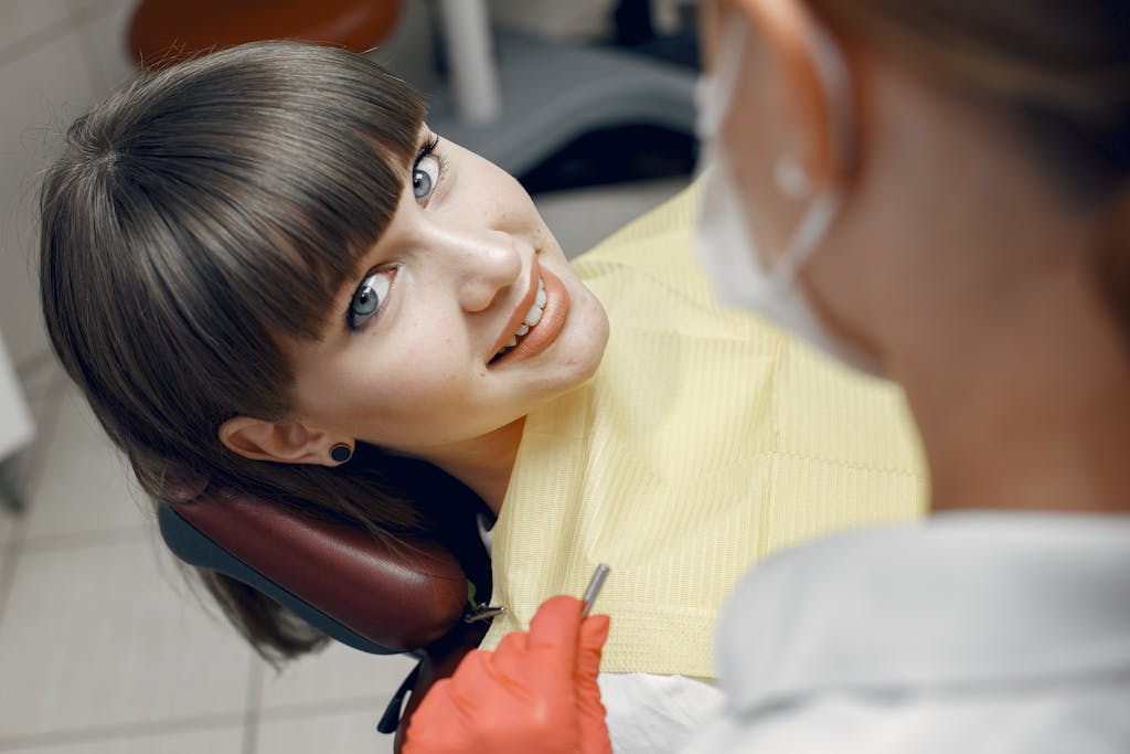 A young woman smiles while seated in a dentist chair during a dental check-up.