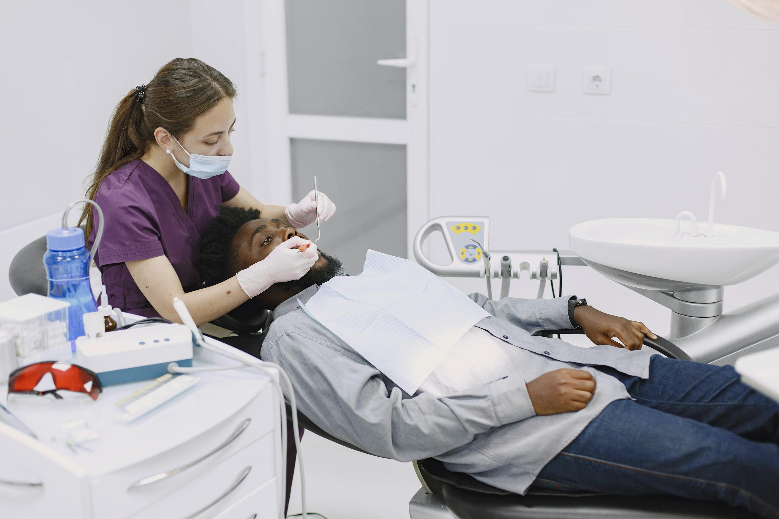 Female dentist performing a dental checkup on a male patient in a modern clinic.